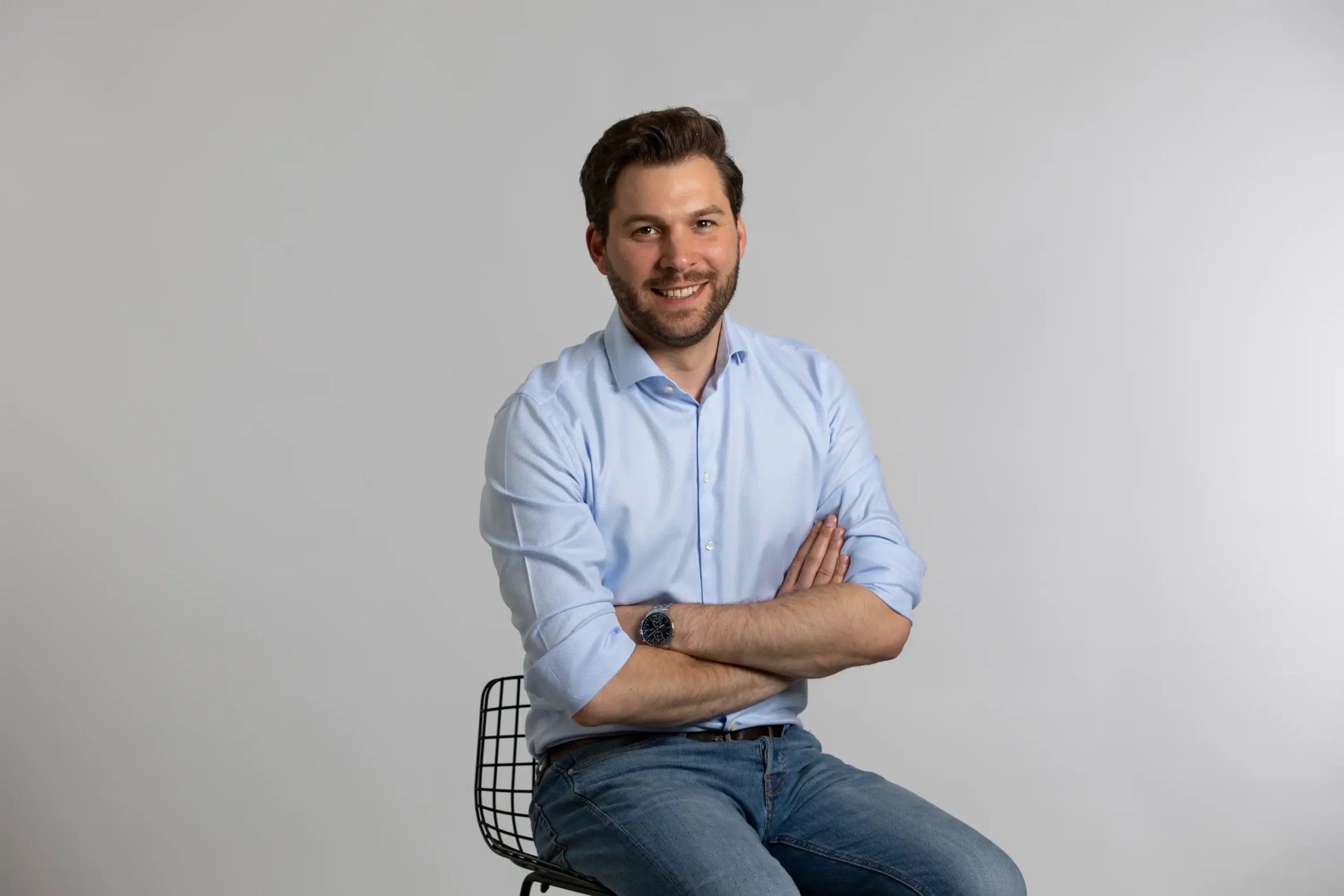 Seminare und Veranstaltungen für Zahnmediziner mit Jens Becker Die Grafik zeigt den Finanzberater Jens-Frederik Becker lächelnd auf einem Stuhl sitzen